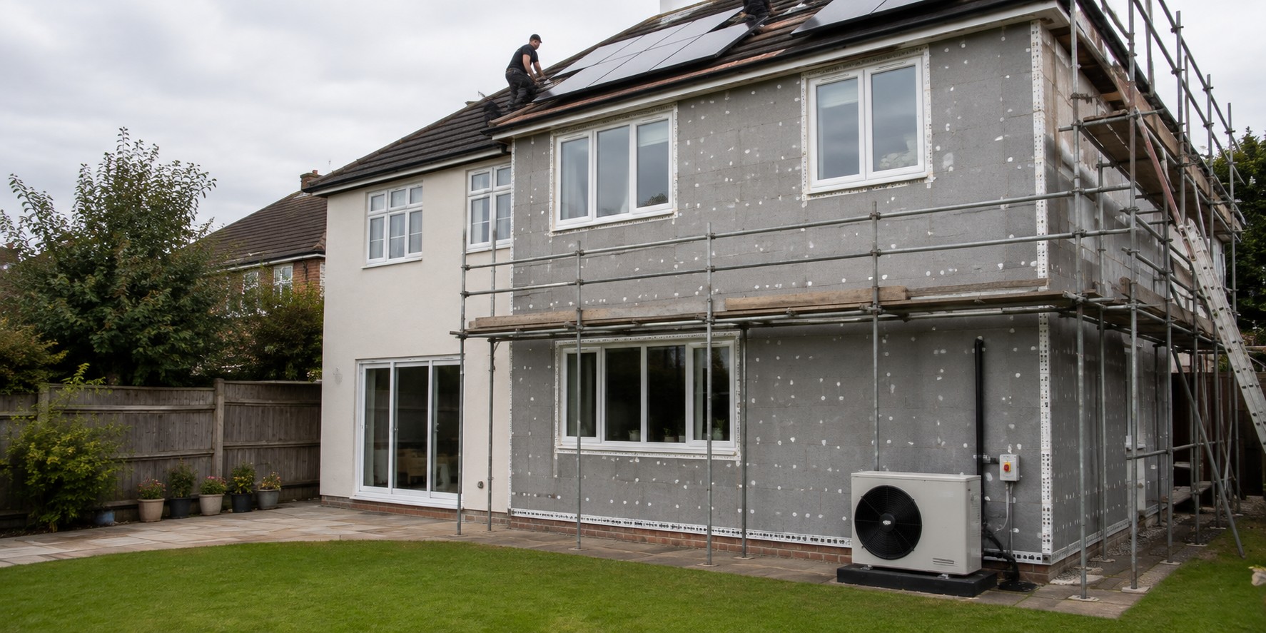 A house mid-retrofit with wall insulation, scaffolding and solar panels going on